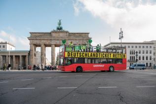 Mit der Forderung “Deutschlandticket retten!” auf der Seite eines roten Doppeldeckerbusses demonstriert Greenpeace gemeinsam mit anderen Umwelt- und Sozialverbänden vor der CDU-Zentrale und an anderen Orten in Berlin. Auf der anderen Seite des Busses steht: „Mehr Bus & Bahn“, auf der Rückseite sind stilisierte öffentliche Verkehrsmittel auf einem grünen Herzen zu sehen, dort steht: „Ein Herz für Öffis“. Die Linienanzeige vorn am Bus zeigt: "1A Klimaschutz“.