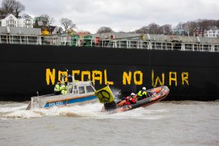 Mit Schlauchbooten und dem Aktionsschiff MS Beluga protestieren Greenpeace-Aktivist:innen im Hamburger Hafen gegen russische Kohleimporte, In zwei Meter hohen Buchstaben schreiben sie  "No Coal No War" auf die Seite des Kohlefrachters "Grant T".