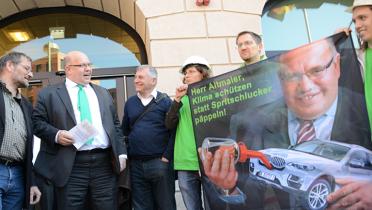 Umweltminister Altmeier trifft auf Aktivisten mit einem Protest-Banner gegen "Spritschlucker"