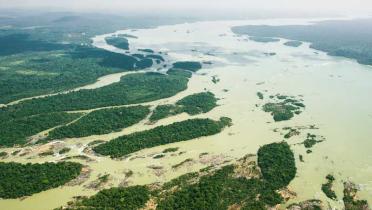 Luftaufnahme des Tapajós. Der Fluss windet sich kurz vorm Horizont in einer Rechtskurve; er ist durchzogen von kleinen Inseln, die - wie auch die Flussufer - dicht von Bäumen bestanden sind.