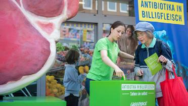 Greenpeace-Aktivistin mit Lidl-Kundin und Schwarzlicht-Vorrichtung