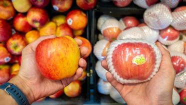 Apfel unverpackt neben Apfel in Plastik