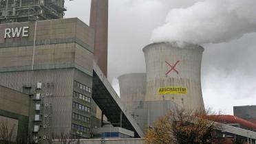 Rotes Kreuz auf dem Kühlturm von Neurath, darunter Banner mit Aufschrift "Abschalten"