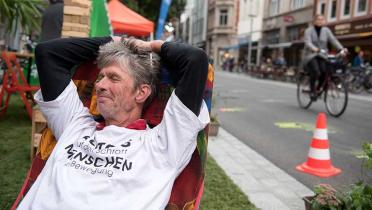 Park(ing) Day: Ein Mann in einem auf einem Rollrasen gestellten Liegestuhl