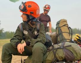 Eine Frau sitzt in Feuerwehr-Ausrüstung auf einem Feld