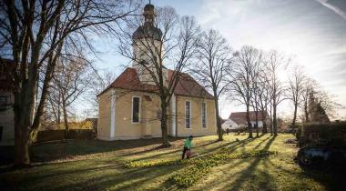 Vor der Dorfkirche in Pödelwitz zeigt jetzt ein X aus Osterglocken: die Menschen wollen nicht, dass das Dorf für die Braunkohle abgerissen wird.