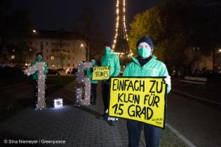 Im Hintergrund ein navhgebauter Eifelturm; im Vordergrund eine Frau mit dem Banner: Einfach zu klein für 1.5 Grad