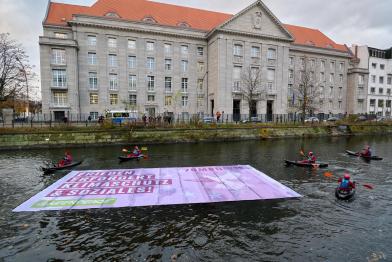 Greenpeace-Aktive protestieren mit Kajaks und einem Schwimmbanner vor dem Verteidigungsministerium