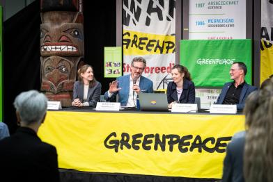 Hinter einem Tisch sitzen im Atrium des Greenpeace-Büros die Sprecher:innen der Pressekonferenz: