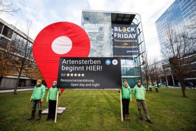 Protestierende mit Googlemaps-Pin vor Amazon Konzernzentrale am Black Friday