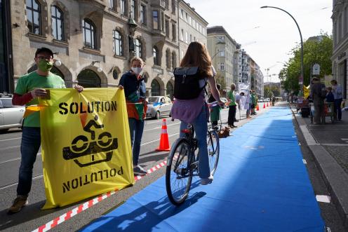 Für die bundesweite Familienfahrraddemonstration "Kidical Mass" richten Greenpeace-Aktivist:innen nun auch in Berlin geschützte Radwege ein. Auf einer Fahrspur der zwei-/dreispurigen Straße schützen sie radelnde Familien mit einer Menschenkette vor dem Autoverkehr. 