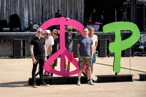 Bandmitglieder der Beatsteaks stehen neben einem großen Peace-Zeichen