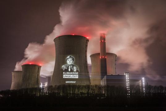 Greenpeace Aktivist:innen projizieren eine Botschaft mit einem Plädoyer für mehr Klimaschutz auf den Kühlturm des RWE-Kohlekraftwerks Neurath. Die Botschaft lautet: "Klimakrise ein ungelöstes Problem!" unter den Porträts von Bundeswirtschafts- und Energieminister Peter Altmaier, Bundesverkehrsminister Andreas Scheuer, Bundeskanzlerin Angela Merkel und der SPD-Vorsitzenden Andrea Nahles.