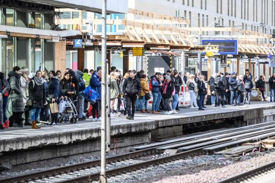 Menschen warten an einem vollen Bahnsteig