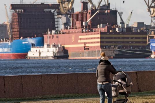 Mutter mit Kinderwagen in unmittelbarer Nähe zum schwimmenden Atomkraftwerk Akademik Lomonosov in St. Petersburg, Russland