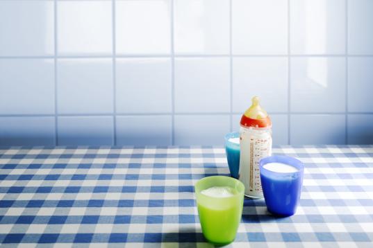 Baby-Milchflasche und mit Milch gefüllte Becher stehen auf einem Tisch, Nov. 2010.