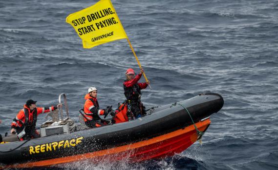 Greenpeace-Aktive mit Banner auf einem Boot