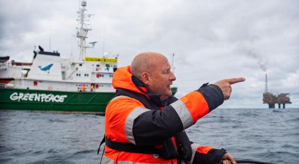 Greenpeace-Meeresexperte Christian Bussau in Rettungsweste auf dem Meer vor Greenepace-Schiff Esperanza