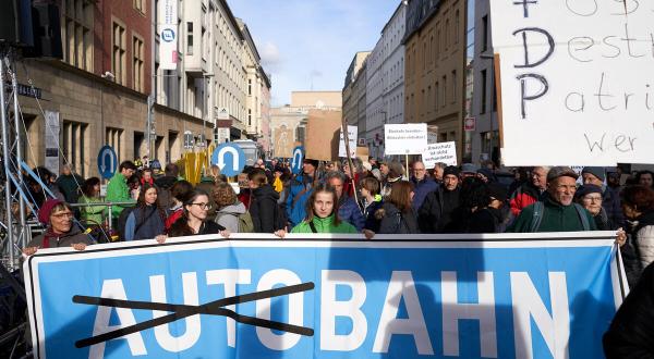 Demonstrierende halten ein großes Banner: Das Wort Auto ist in dem Schriftzug Autobahn durchgestrichen