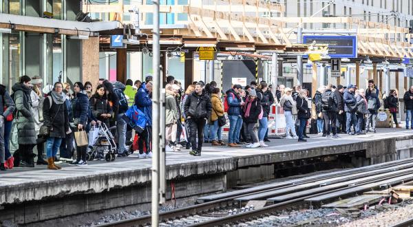 Menschen warten an einem vollen Bahnsteig