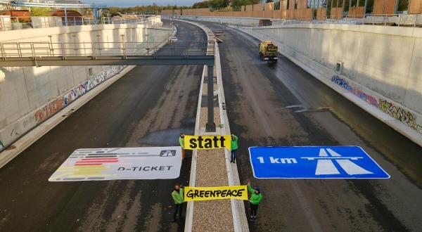 Auf der im Bau befindlichen Berliner Stadtautobahn A 100 legen Aktive ein 8 x 5 m großes Deutschlandticket neben ein ebenso großes Autobahn-Logo auf der Gegenfahrbahn