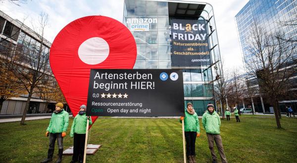 Protestierende mit Googlemaps-Pin vor Amazon Konzernzentrale am Black Friday