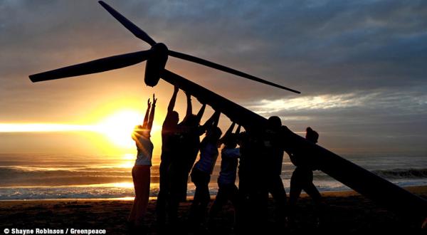 Menschen stellen eine Windturbine auf.