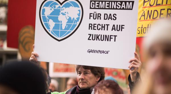 Demonstrant mit Schild "Gemeinsam für das Recht auf Zukunft"