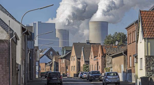 Dampfschwaden des Kraftwerks Neurath über Häusern