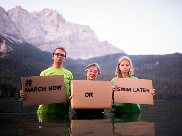 reenpeace-Jugendliche Maria Meyer (16) aus Augsburg und Cedric Hinrich (15) aus Karlsruhe zusammen mit Klima-Aktivistin Gisela Johannsen (87) stehen huefttief im Wasser des Eibsee unterhalb der Zugspitze.