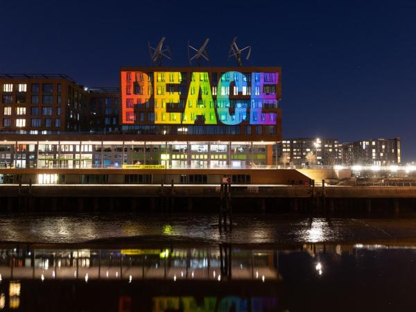 Eine Projektion mit den Buchstaben PEACE (FRIEDEN) leuchtet in Regenbogenfarben auf der Zentrale von Greenpeace Deutschland.