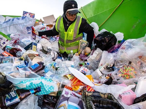 Mensch inmitten Plastikmüllhalde